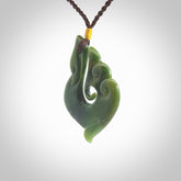 This photo shows a beautiful jade swan hook suspended from a hand plaited brown cord. This swan hook was carved for us by Jen Hung who is a master jade carver from New Zealand.